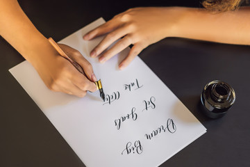 dream big set goals take action. Calligrapher Young Woman writes phrase on white paper. Inscribing...