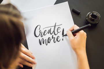 Creat more. Calligrapher Young Woman writes phrase on white paper. Inscribing ornamental decorated...