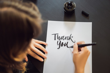 Thank you. Calligrapher Young Woman writes phrase on white paper. Inscribing ornamental decorated...