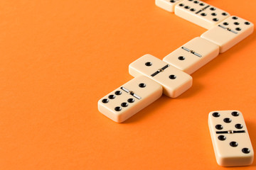 Playing dominoes on a orange table. Domino effect.