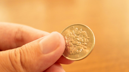 Fototapeta premium Close up the 100 Japanese Yen Coin on Finger
