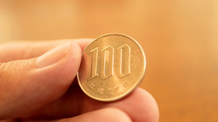 Close up the 100 Japanese Yen Coin on Finger