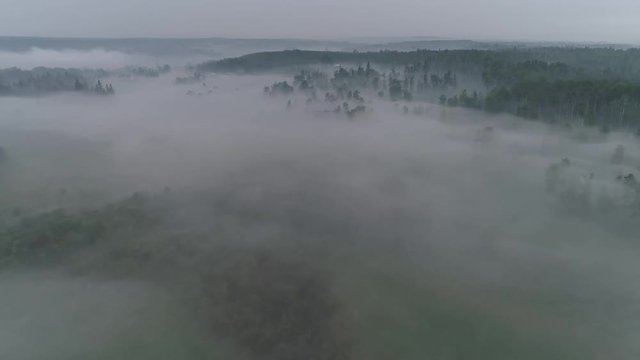 Low visibility  aerial view flying through fog and smoke to reveal an Alberta country farm location.