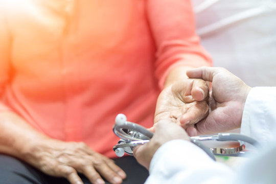 Parkinson and Alzheimer female senior elderly patient with caregiver in hospice care. Doctor hand with stethoscope check up older woman people. Old aging person seeing medical physician in hospital.