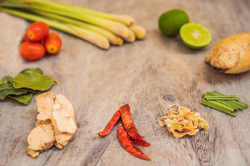 Ingredients for popular Thai soup Tom-yum kung. Lime, galangal, red chili, cherry tomato, lemongrass and kaffir lime leaf on black board . Flat lay. View from above