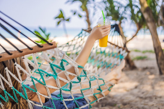 Young Woman On The Beach In A Hammock With A Drink