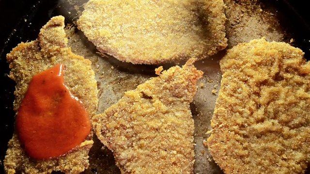Milanesa Napolitana being prepared, tomate sauce being poured,  traditional Argentina meal