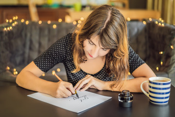 Good morning. Calligrapher Young Woman writes phrase on white paper. Inscribing ornamental decorated letters. Calligraphy, graphic design, lettering, handwriting, creation concept