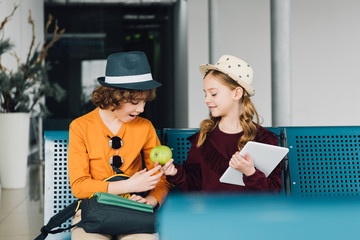 cute preteen kids sitting in waiting hall and sharing apple