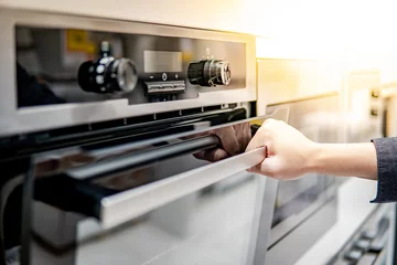 Foto op Plexiglas Male hand opening oven door in the kitchen showroom. Buying cooking appliance for domestic kitchen. Home improvement concept © zephyr_p