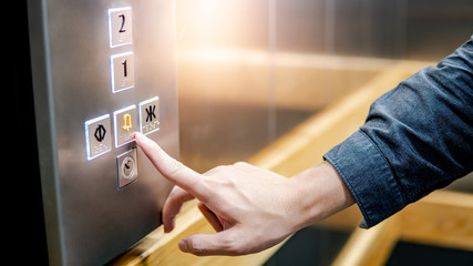 Male forefinger pressing on emergency stop and alarm button in elevator (lift). Mechanical engineering concept - obrazy, fototapety, plakaty