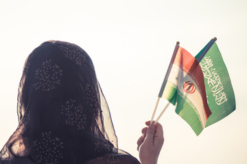 Muslim woman in scarf with Saudi Arabia and Iranian flags of at sunset background.Concept.saudi