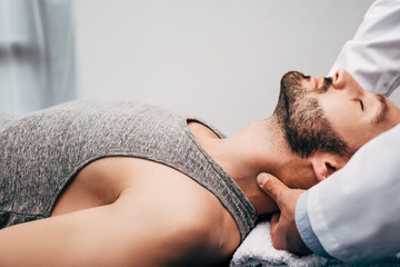 chiropractor massaging neck of man lying on towel in hospital - obrazy, fototapety, plakaty