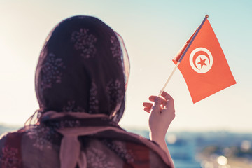 Muslim woman in scarf with Tunisia flag of at sunset.Concept