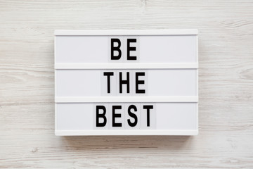 'Be the best' words on a modern board on a white wooden background. Flat lay, overhead, top view. Close-up.