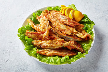 Fried in batter capelins on a plate, close-up