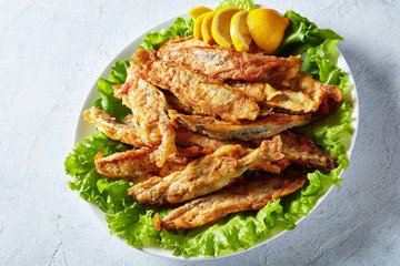 Fried in batter capelins on a plate, close-up