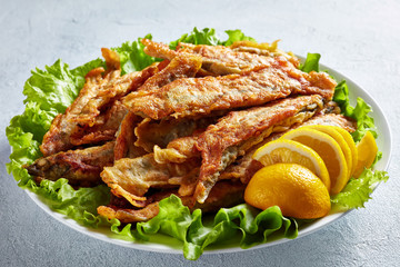 Fried in batter capelins on a plate, close-up