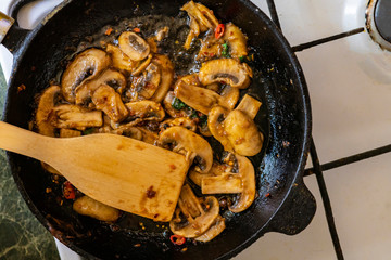 mushroom and red pepper sauce in a pan cooking with mixing wooden paddles