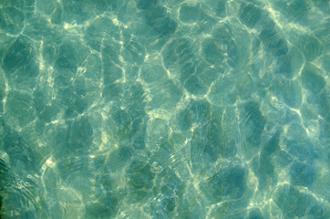 Fototapeta na wymiar The sun pattern is a play of light and shadow in the form of highlights, spots and streaks on the calm clear surface of the emerald transparent sea water