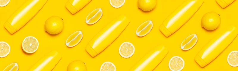 Kreatives Sommerkonzept. Gelbe kosmetische Flaschenbehälter, frische Zitruszitrone auf gelbem Hintergrund, Draufsicht, flacher Kopienraum. Leeres Etikett für Branding-Mock-up Sonnenschutzmittel für natürliche Schönheitsprodukte. © olgaarkhipenko