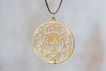 Brass metal tree shape pendant round mandala on neutral background