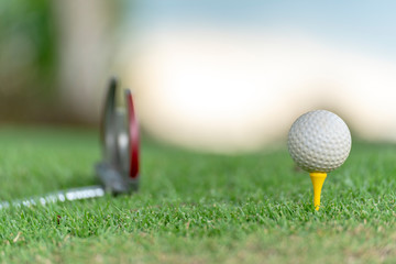 Golf ball on tee in golf field with recreation sport training course.