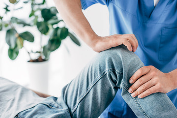 Cropped view of Physiotherapist massaging leg of patient in hospital