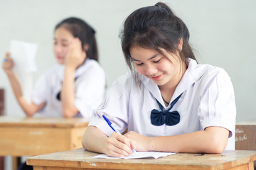 Smile young girl student reading and writing exam with not stress. © arrowsmith2