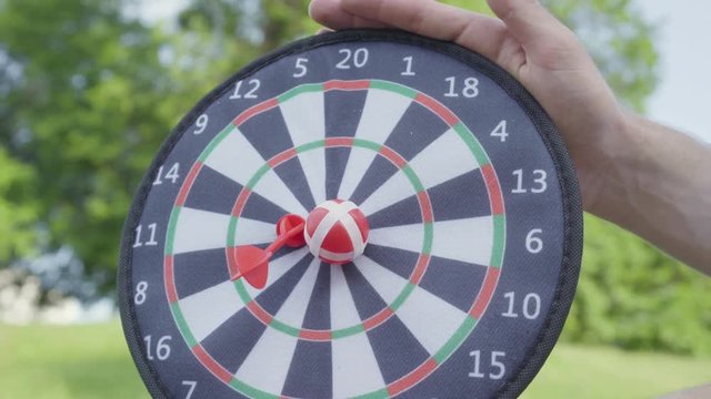 Closeup father hands holding darts while his son throwing darts and ball on a magnet in the circles. Family leisure outdoors. Father and a kid spend time together