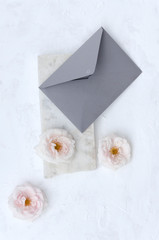 Top view of craft envelope, beautiful delicate roses, piece of marble on the white background