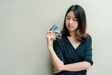 Asian beautiful woman Wearing a black shirt Have a credit card in hand Happy face Standing in the gray wall