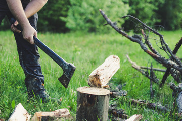 The guy is cutting an old tree in the mountains with an ax. Ukrainian Carpathian Mountains. Bonfire. Tourism. Ax