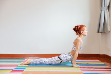 Side view of young attractive caucasian woman in black and white sportswear practicing or exercise yoga indoor. balance between body and mental. (healthy life concept)