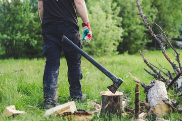 The guy is cutting an old tree in the mountains with an ax. Ukrainian Carpathian Mountains. Bonfire. Tourism. Ax