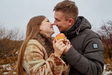 Romantic couple in love on autumn or winter walk with apple