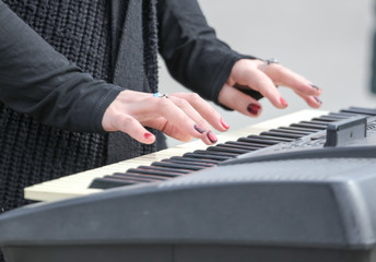 The hands of the girl on the keyboard synthesizer