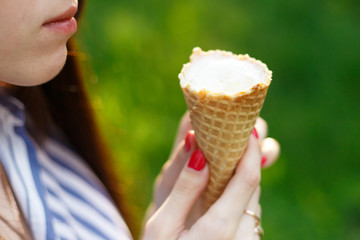 Young beautiful girl with long flowing hair eat ice cream. Bright sunny day. Natural background. Soft focus. Ice cream close-up