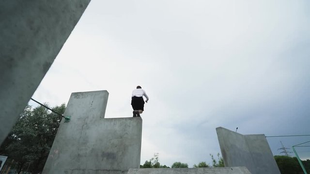 Young man runs and jumps over obstacles, parkour on workout training area, free running.