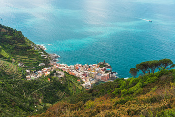 Fototapeta na wymiar Stunning view over the colorful town of Vernazza in Cinque Terre, Italy, as seen from the hiking trail passing above it. Landscape of an old italian coastal village at the Ligurian Sea.