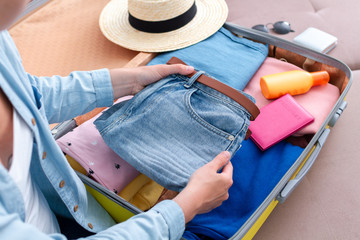 Woman traveler packing clothes in a suitcase for a new journey. Luggage for travel holidays and vacation.