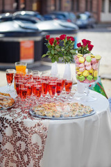 Glassware with colorful macarons and drinks on a white table