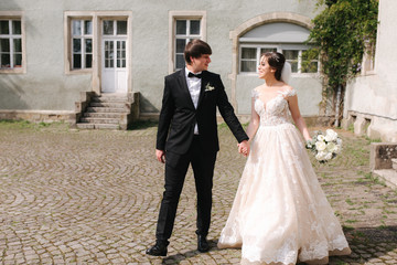 Naklejka premium Happy just married couple in wedding clothes walking near the castle