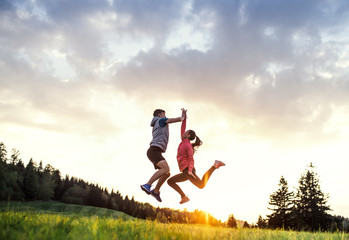 Active young couple jumping after doing exercise in nature at sunset.