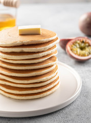 Pancakes stack with butter and honey. Grey backround.