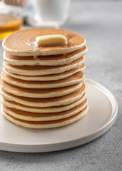 Pancakes stack with butter and honey. Grey backround.