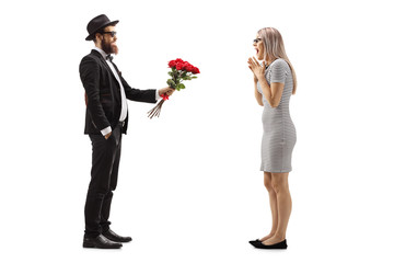 Man in a suit giving a bouquet of red roses to a surprised woman