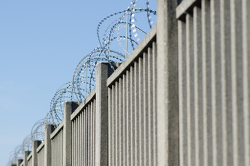 Wall or fence with barbed wire of sharp points that are difficult to climb over.