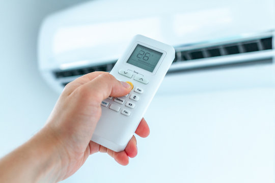 Air Conditioner Temperature Adjustment With Remote Controller In Room At Home.