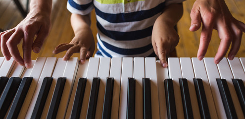 Children's and women's hands on the piano keys.